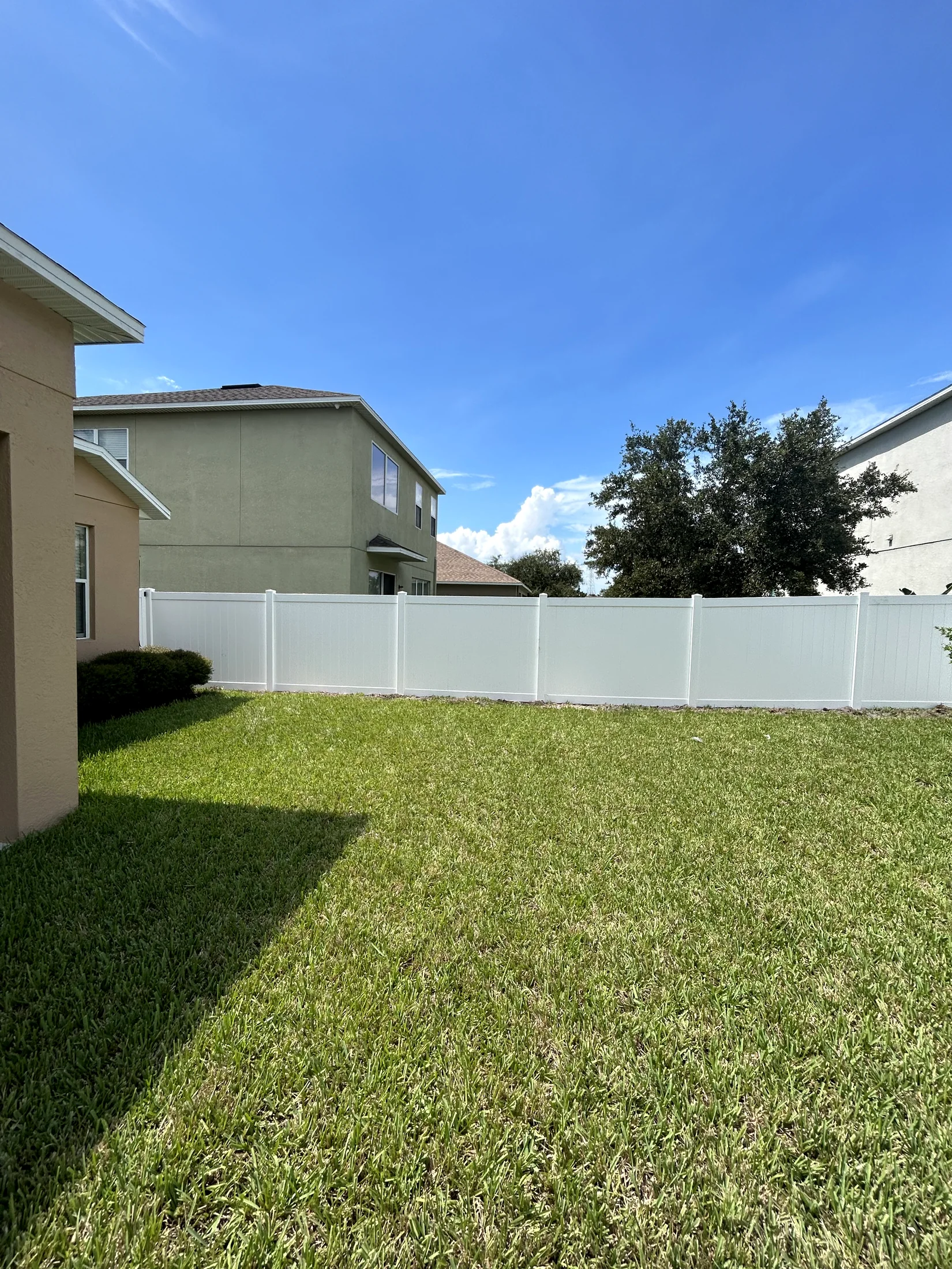 White vinyl privacy fence installed beside a two-story home